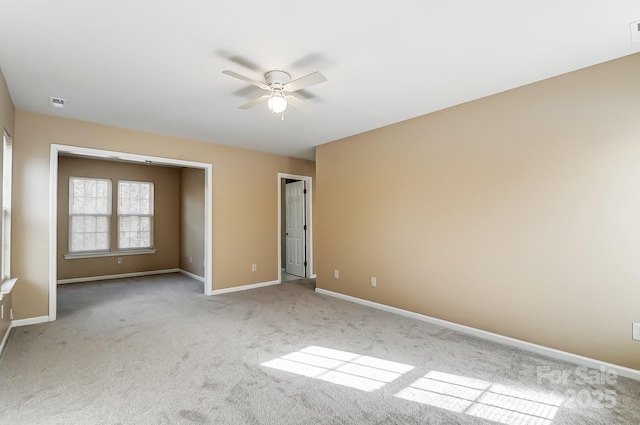 spare room with a ceiling fan, light carpet, visible vents, and baseboards