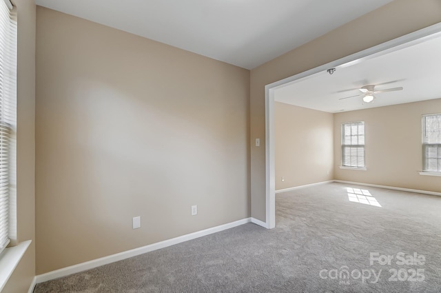 carpeted spare room featuring ceiling fan and baseboards