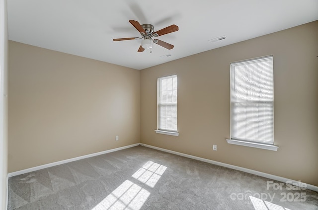 spare room with light carpet, visible vents, a ceiling fan, and baseboards