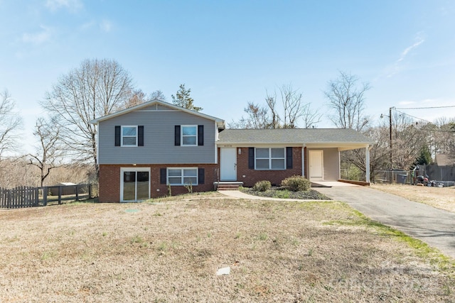 tri-level home featuring fence, aphalt driveway, an attached carport, and brick siding