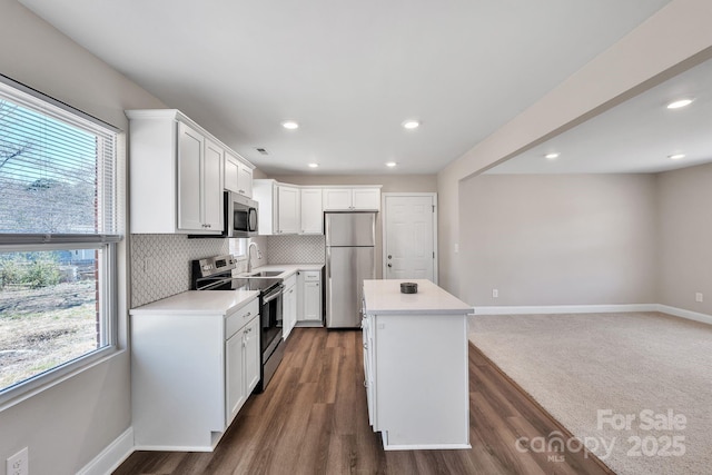 kitchen with stainless steel appliances, a center island, light countertops, and decorative backsplash