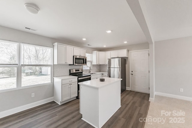 kitchen with stainless steel appliances, a sink, white cabinetry, baseboards, and decorative backsplash