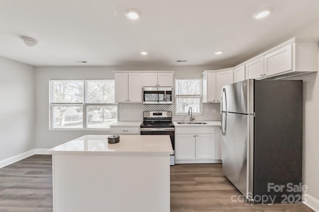 kitchen with stainless steel appliances, white cabinetry, a sink, and tasteful backsplash