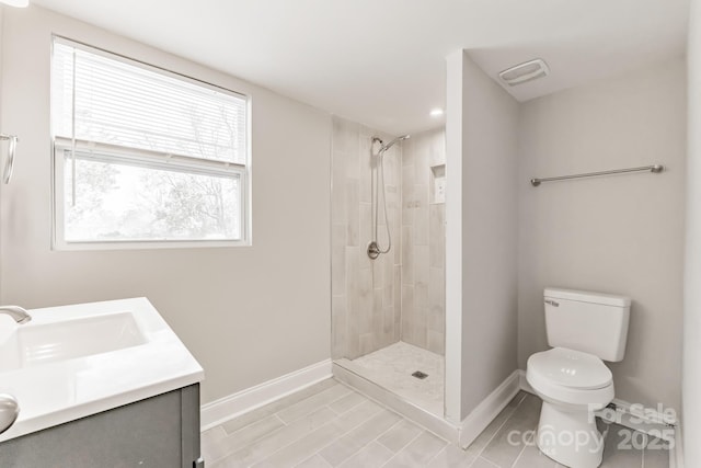 bathroom with toilet, baseboards, and a tile shower