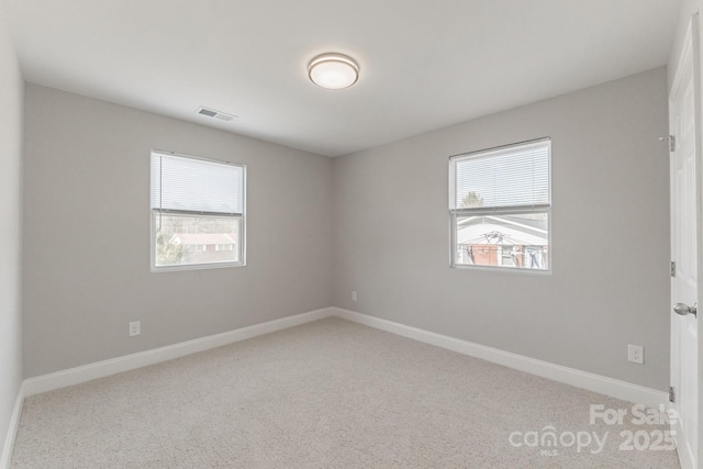 spare room featuring carpet, baseboards, and visible vents