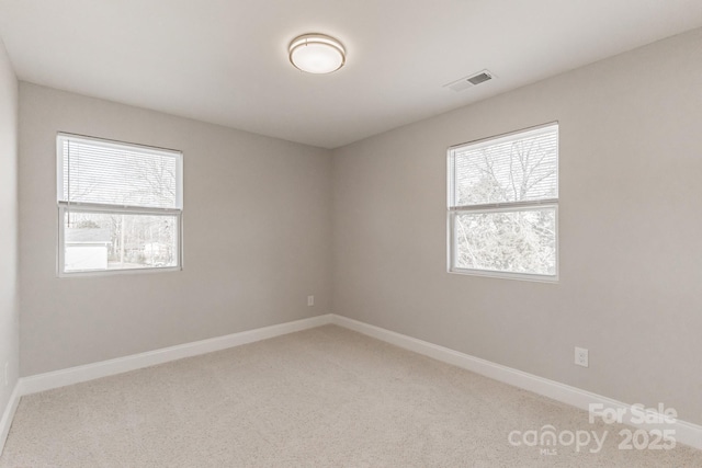 spare room featuring carpet floors, baseboards, and visible vents