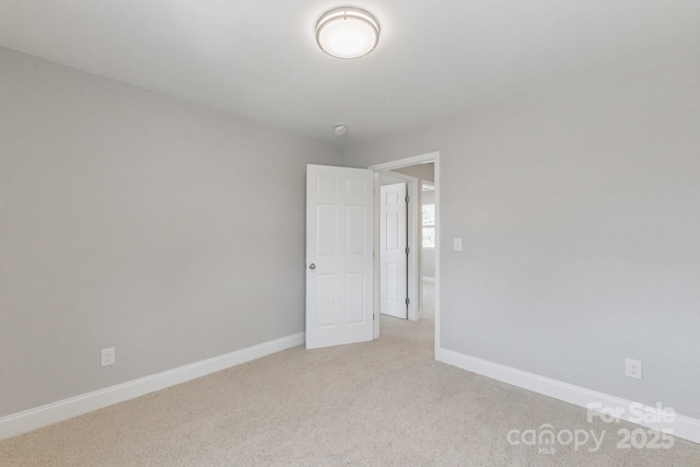 unfurnished room featuring light colored carpet and baseboards