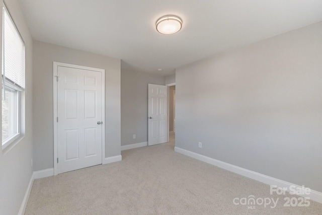 unfurnished bedroom featuring light carpet and baseboards