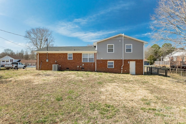 rear view of property with a yard, central AC unit, fence, and brick siding