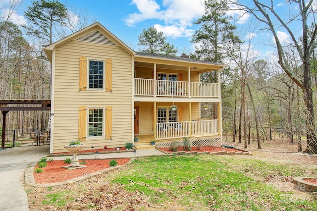 view of front facade with covered porch, driveway, a front lawn, and a balcony