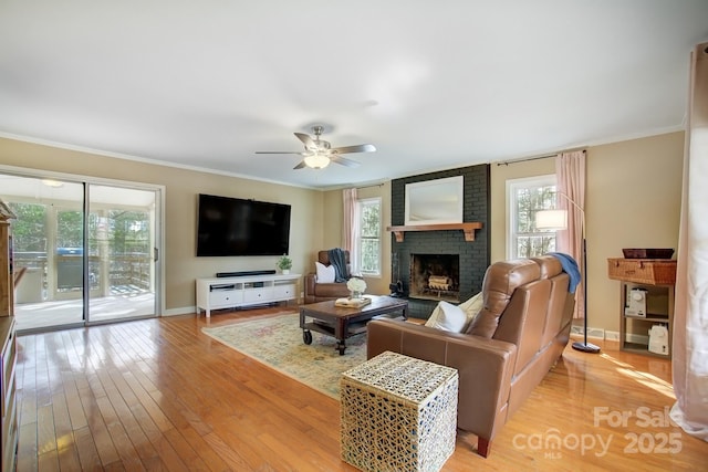 living room featuring ornamental molding, light wood-type flooring, a healthy amount of sunlight, and a fireplace