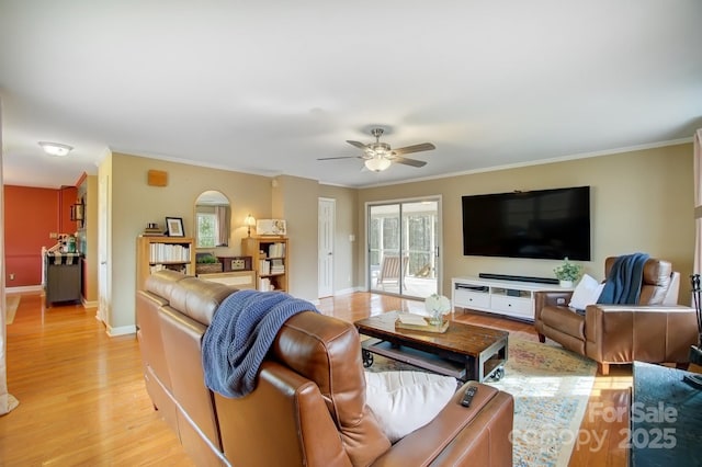 living area featuring light wood-type flooring, ceiling fan, baseboards, and crown molding