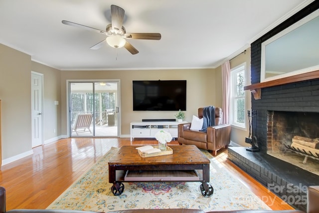 living area featuring ornamental molding, a brick fireplace, plenty of natural light, and wood finished floors