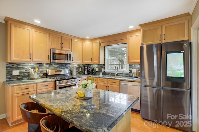 kitchen with appliances with stainless steel finishes, stone countertops, a sink, and light wood-style flooring