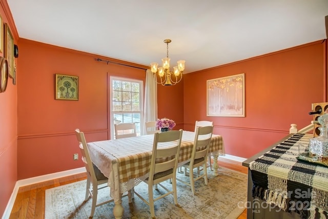 dining room featuring ornamental molding, a notable chandelier, baseboards, and wood finished floors