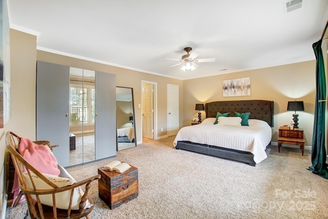 carpeted bedroom featuring a ceiling fan, baseboards, visible vents, and crown molding