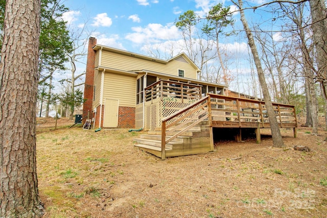 rear view of property with stairs, a chimney, a deck, and brick siding