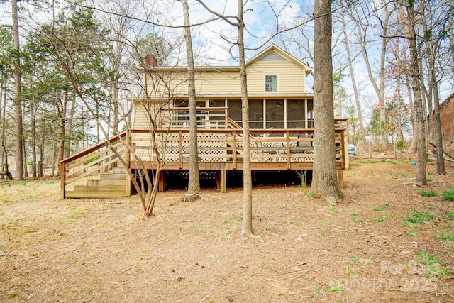 rear view of house featuring a deck, a sunroom, and a chimney