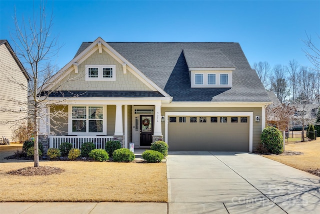 craftsman-style home with covered porch, concrete driveway, a shingled roof, and a garage