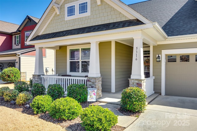 doorway to property featuring a porch, stone siding, roof with shingles, and an attached garage