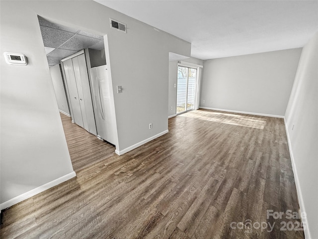 spare room with wood finished floors, visible vents, and baseboards