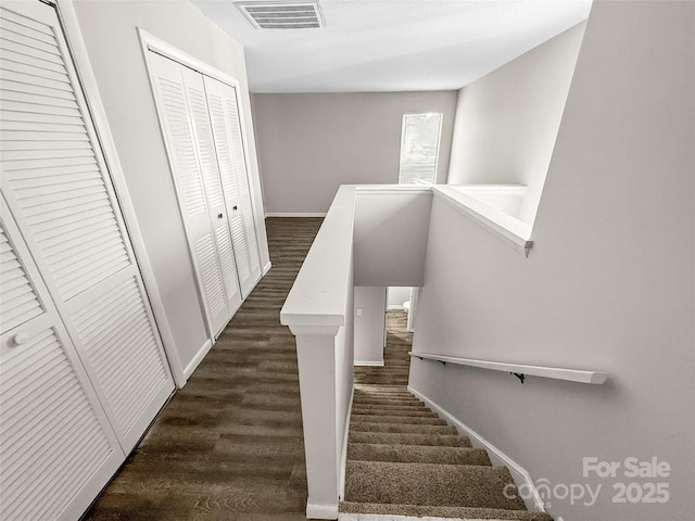 stairway with wood finished floors, visible vents, and baseboards