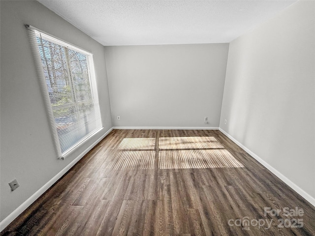 spare room with a textured ceiling, baseboards, and wood finished floors