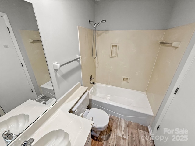 bathroom featuring toilet, vanity, wood finished floors, and shower / bathing tub combination