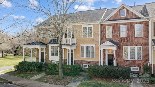 townhome / multi-family property featuring brick siding, a shingled roof, and a front yard