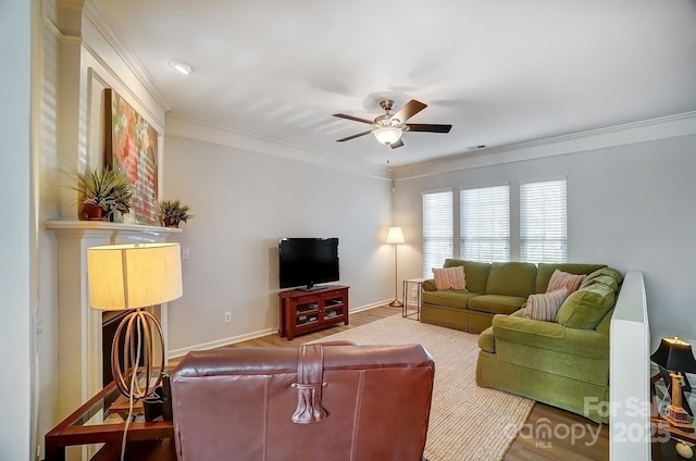 living area with ornamental molding, a ceiling fan, and baseboards