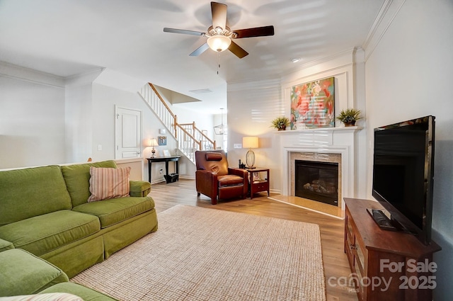 living area featuring ornamental molding, stairway, and light wood-style floors