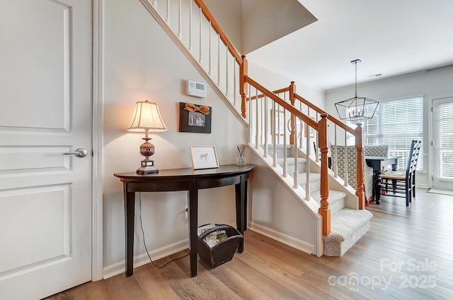 staircase with baseboards, wood finished floors, visible vents, and a notable chandelier