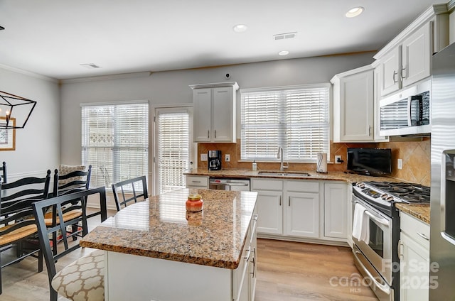 kitchen featuring light stone countertops, white cabinetry, appliances with stainless steel finishes, and a sink