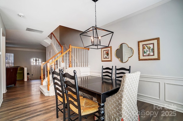 dining room featuring a wainscoted wall, visible vents, ornamental molding, stairway, and dark wood finished floors