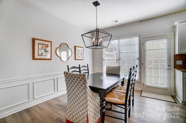 dining room with ornamental molding, light wood finished floors, and visible vents