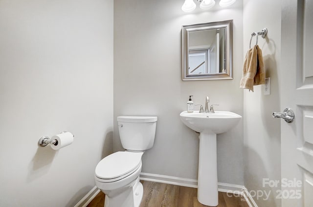 bathroom with baseboards, a sink, toilet, and wood finished floors