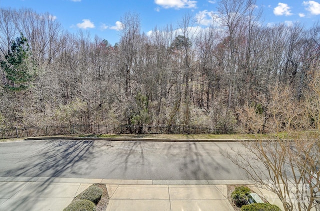 view of road with a wooded view and curbs