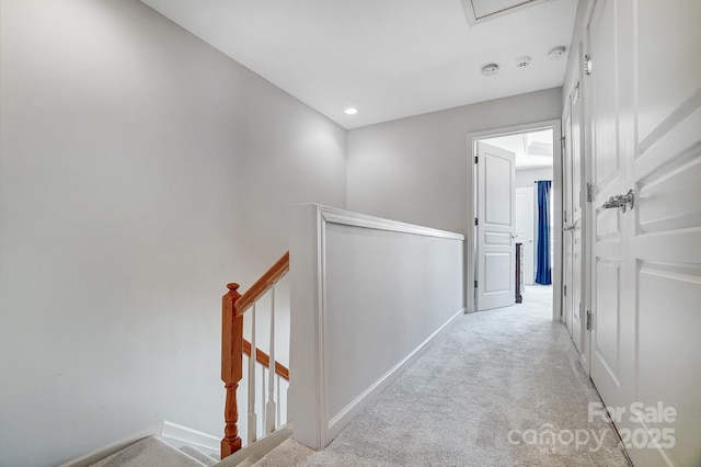 corridor featuring light carpet, baseboards, and an upstairs landing