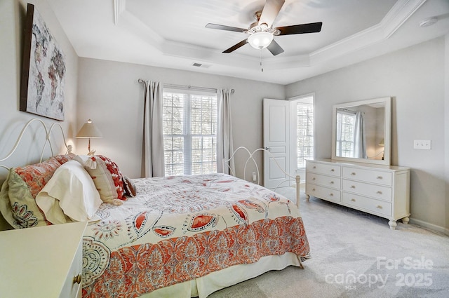 bedroom with ceiling fan, light carpet, visible vents, ornamental molding, and a raised ceiling