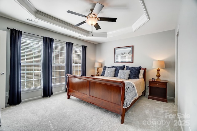 bedroom featuring a tray ceiling, light colored carpet, crown molding, and visible vents