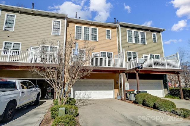 rear view of house with a garage, driveway, and a balcony