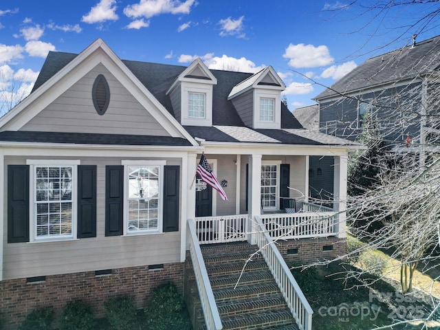 view of front facade featuring covered porch, a shingled roof, crawl space, and stairway