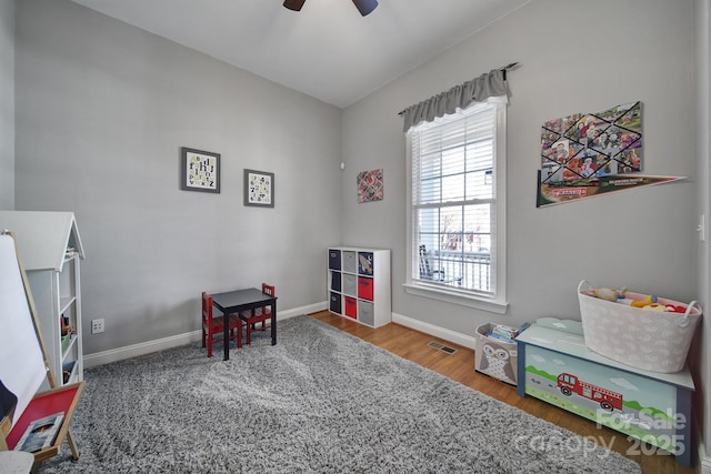 playroom featuring a ceiling fan, visible vents, baseboards, and wood finished floors