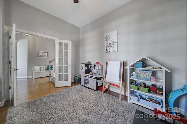 playroom with wood finished floors, a ceiling fan, baseboards, vaulted ceiling, and french doors