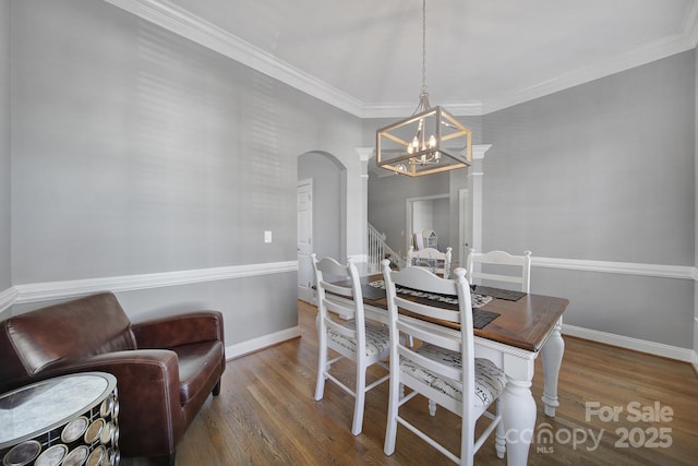 dining space with ornamental molding, arched walkways, baseboards, and wood finished floors