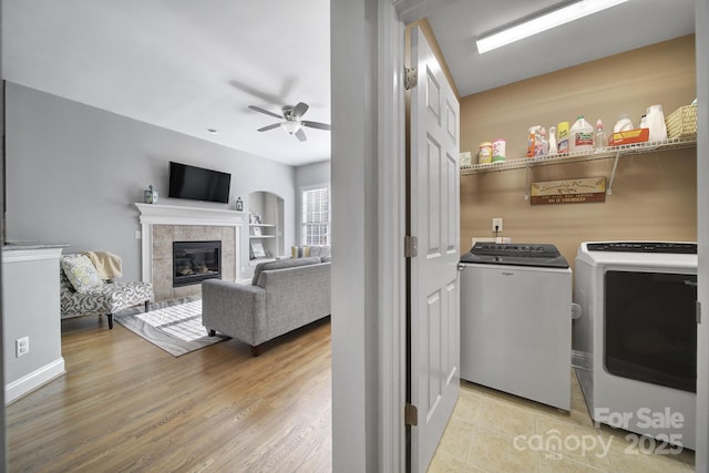 clothes washing area with laundry area, washer and clothes dryer, a ceiling fan, wood finished floors, and a fireplace