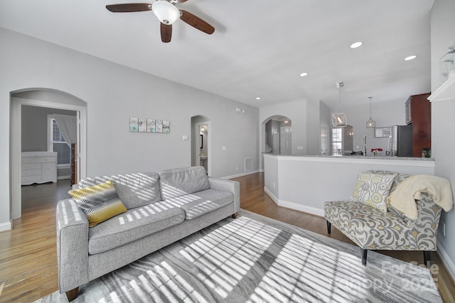 living room with light wood-type flooring, visible vents, arched walkways, and recessed lighting