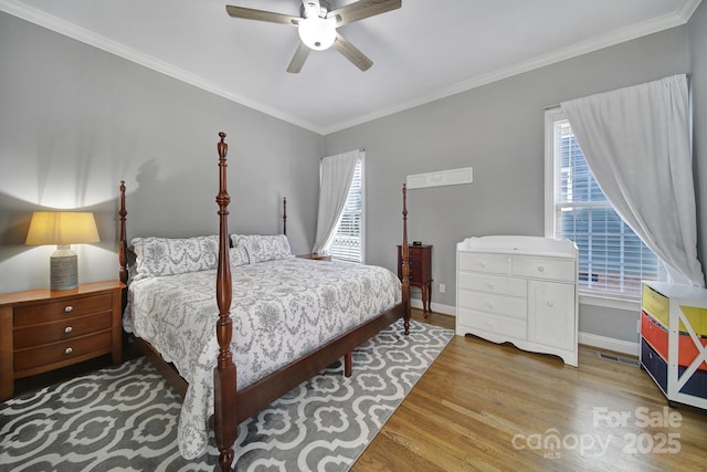 bedroom featuring crown molding, visible vents, ceiling fan, wood finished floors, and baseboards