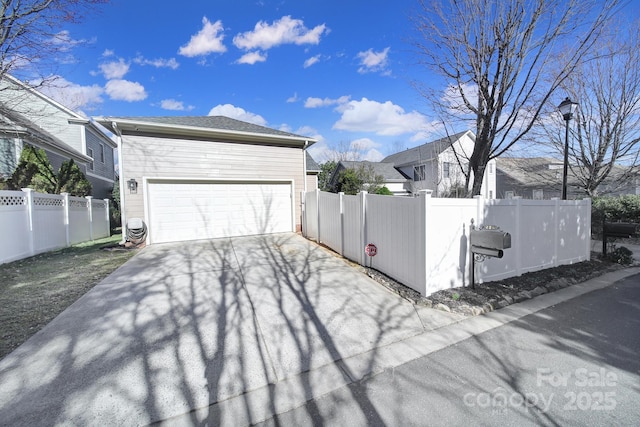 view of side of property featuring driveway and a fenced front yard