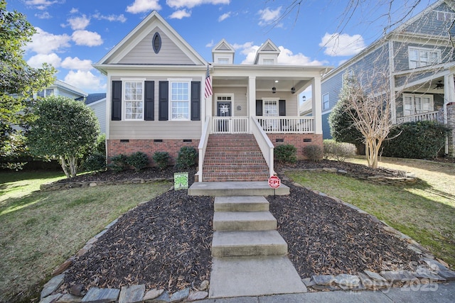 view of front of home with crawl space, covered porch, stairs, and a front yard